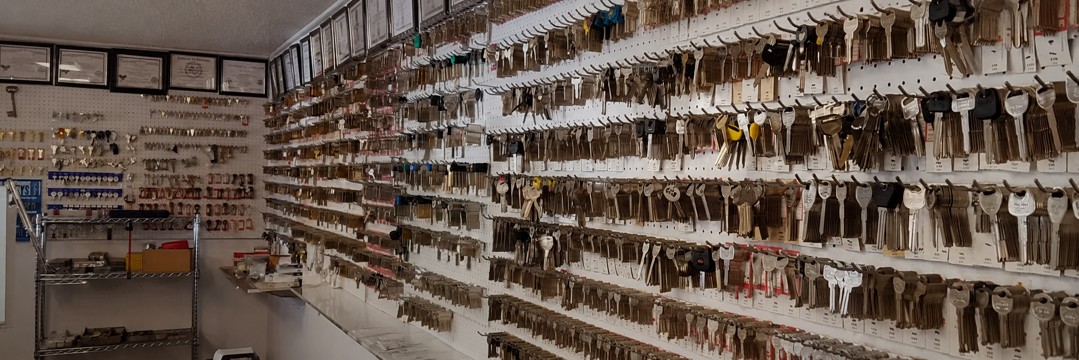 Wall of hundreds of labeled key blanks and locksmith licenses inside Bill's Locksmith Service shop in Marble Falls, TX